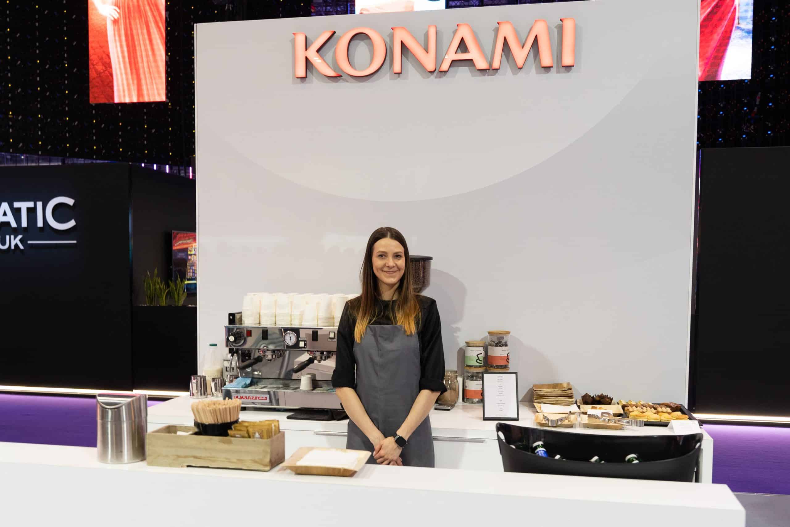 Social espresso barista standing at a large exhibition stand with the coffee set up behind her.