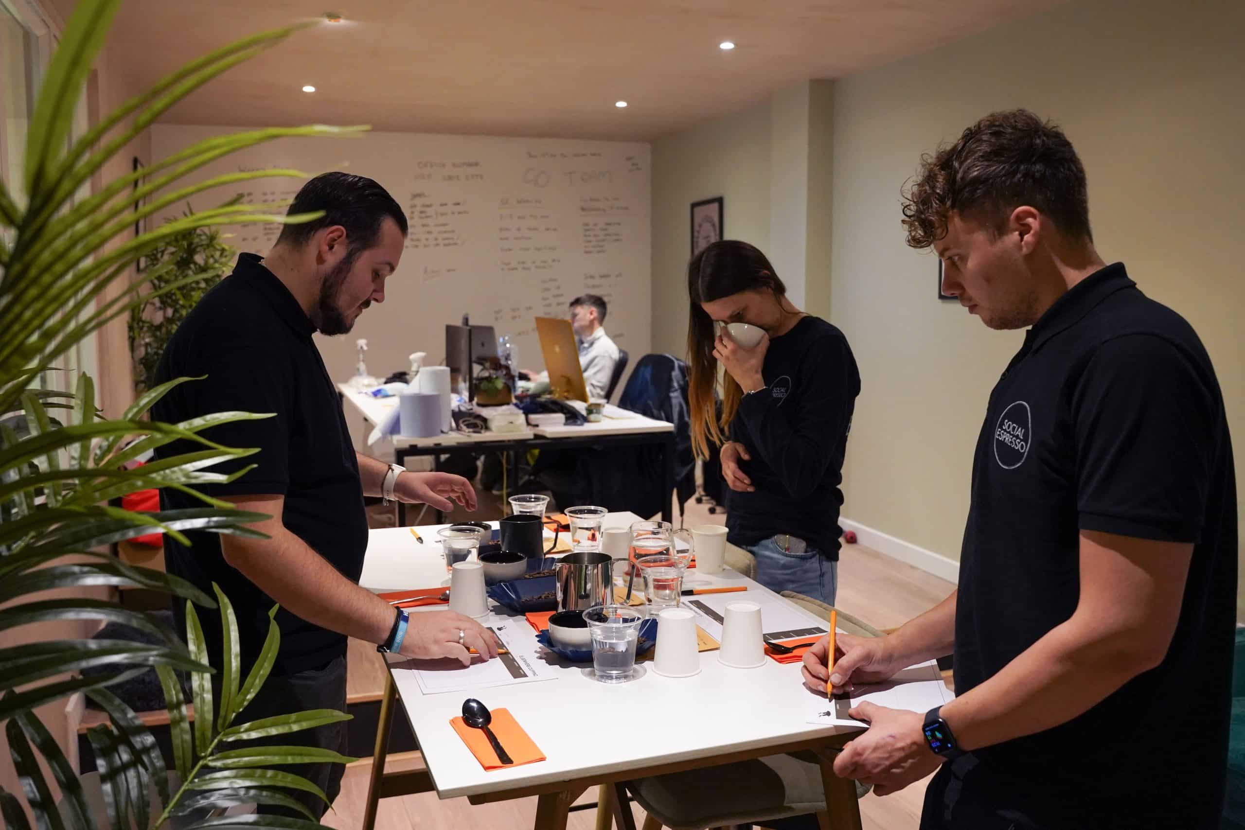 Social Espresso staff standing around a table and cupping different coffees