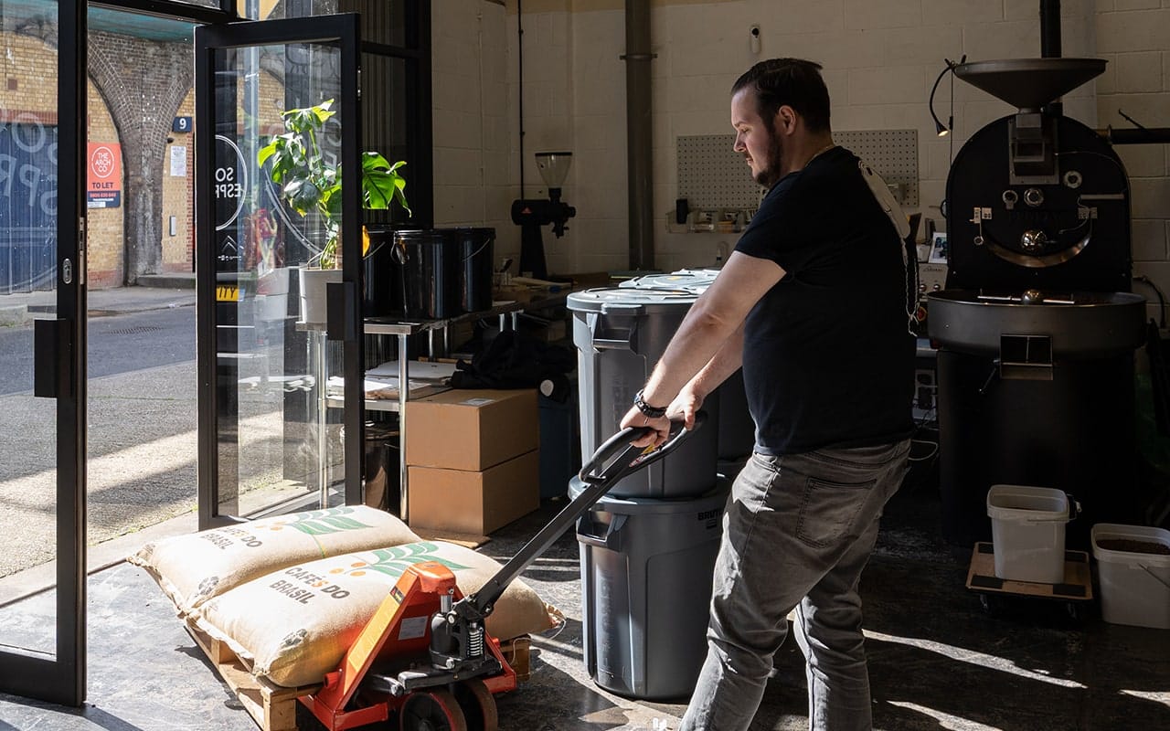 Event barista standing in our coffee roastery, pulling sacks of coffee beans.